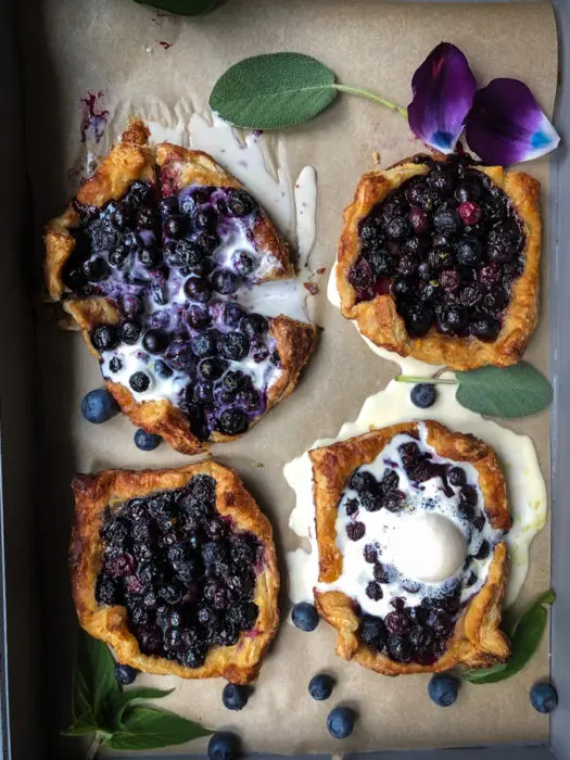 Four blueberry tarts with vanilla ice cream.